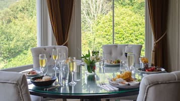 Mesa para dos con una vista panorámica, un jarrón de flores y diferentes platos y bebidas.