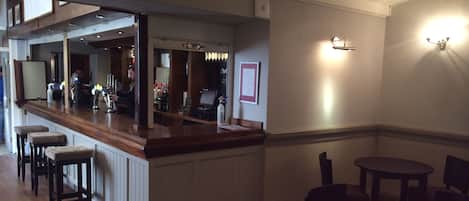 A bar area with stools, a counter, and tables.