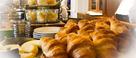A buffet with croissants and fruit cups.