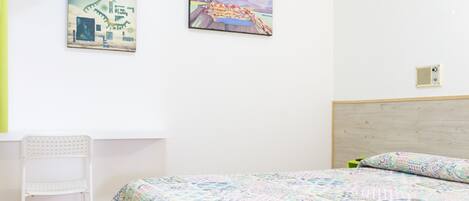 A bedroom with a bed, a chair, and two wall-mounted artworks.