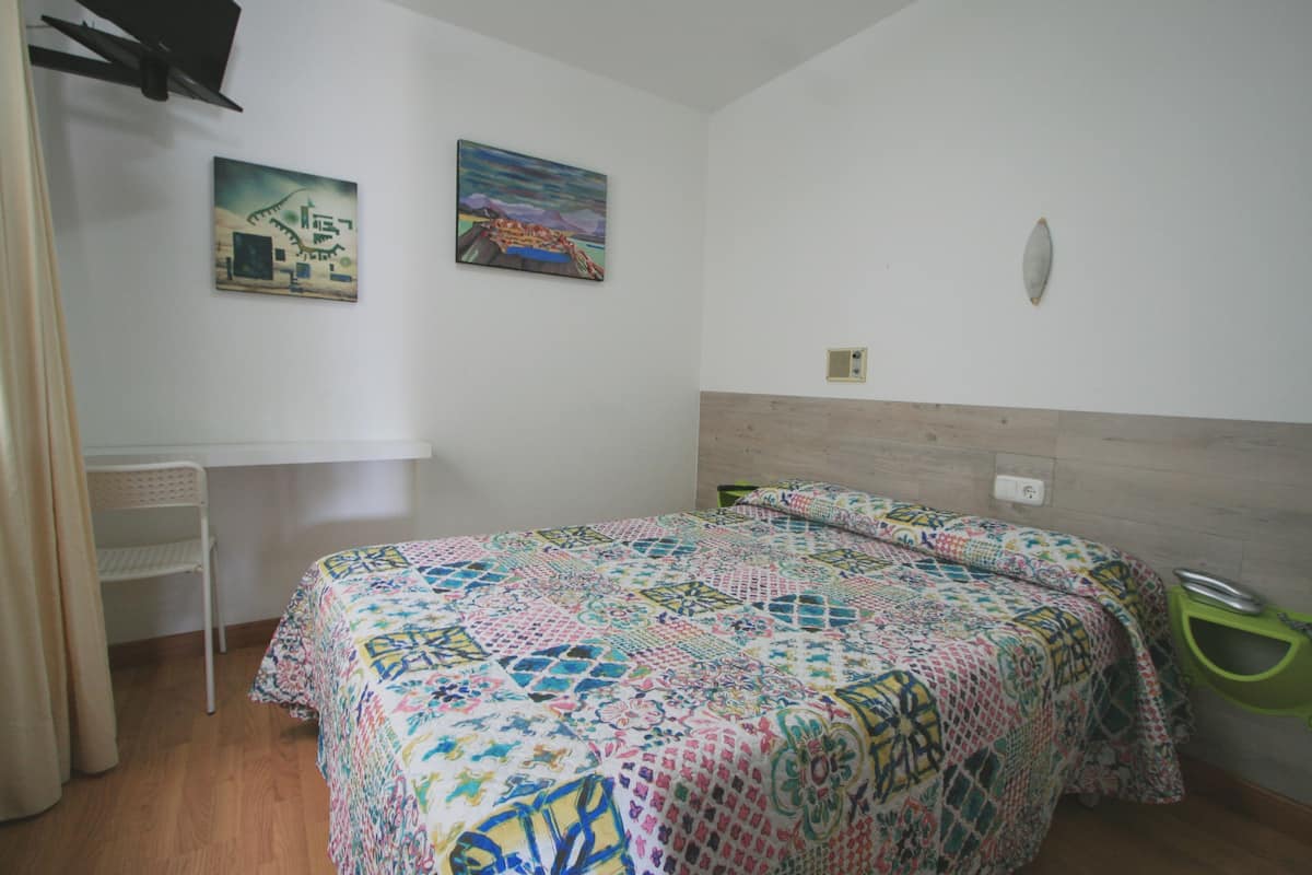 A bedroom with a bed, a chair, and two paintings on the wall.