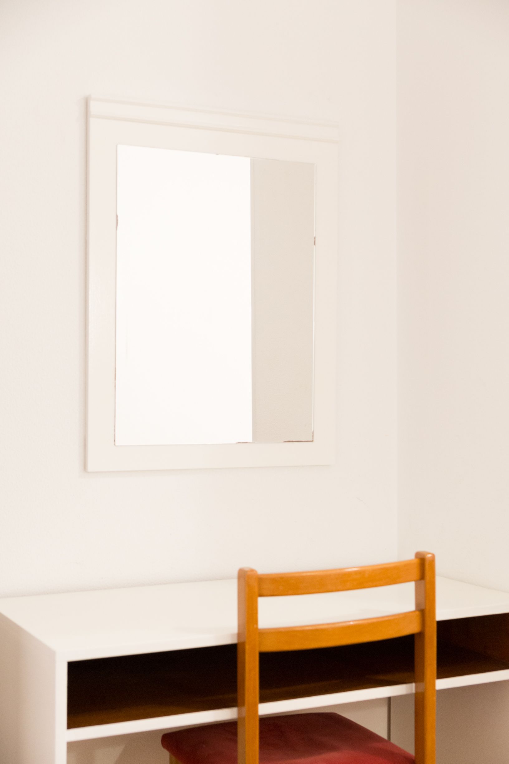 Una habitación con un escritorio blanco y una silla.