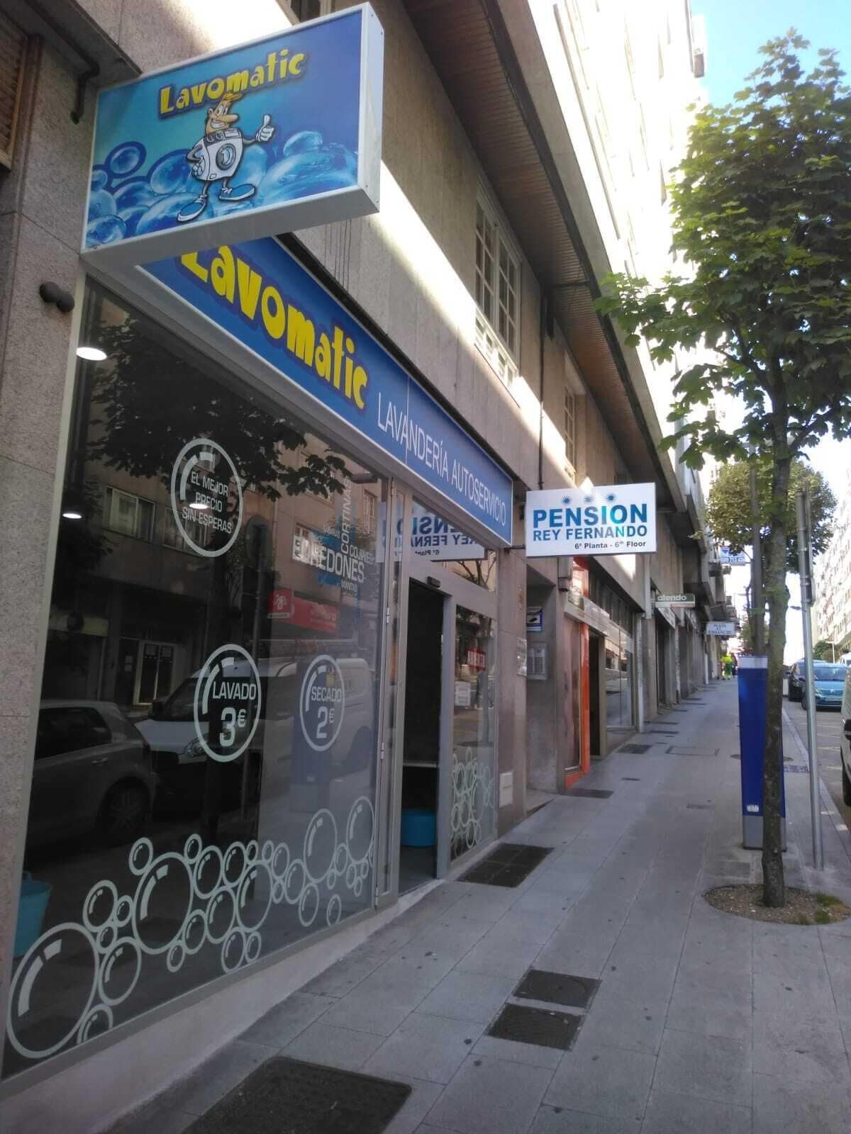 En butik med et skilt for 'Lavomatic' og 'Pension Rey Fernando'.