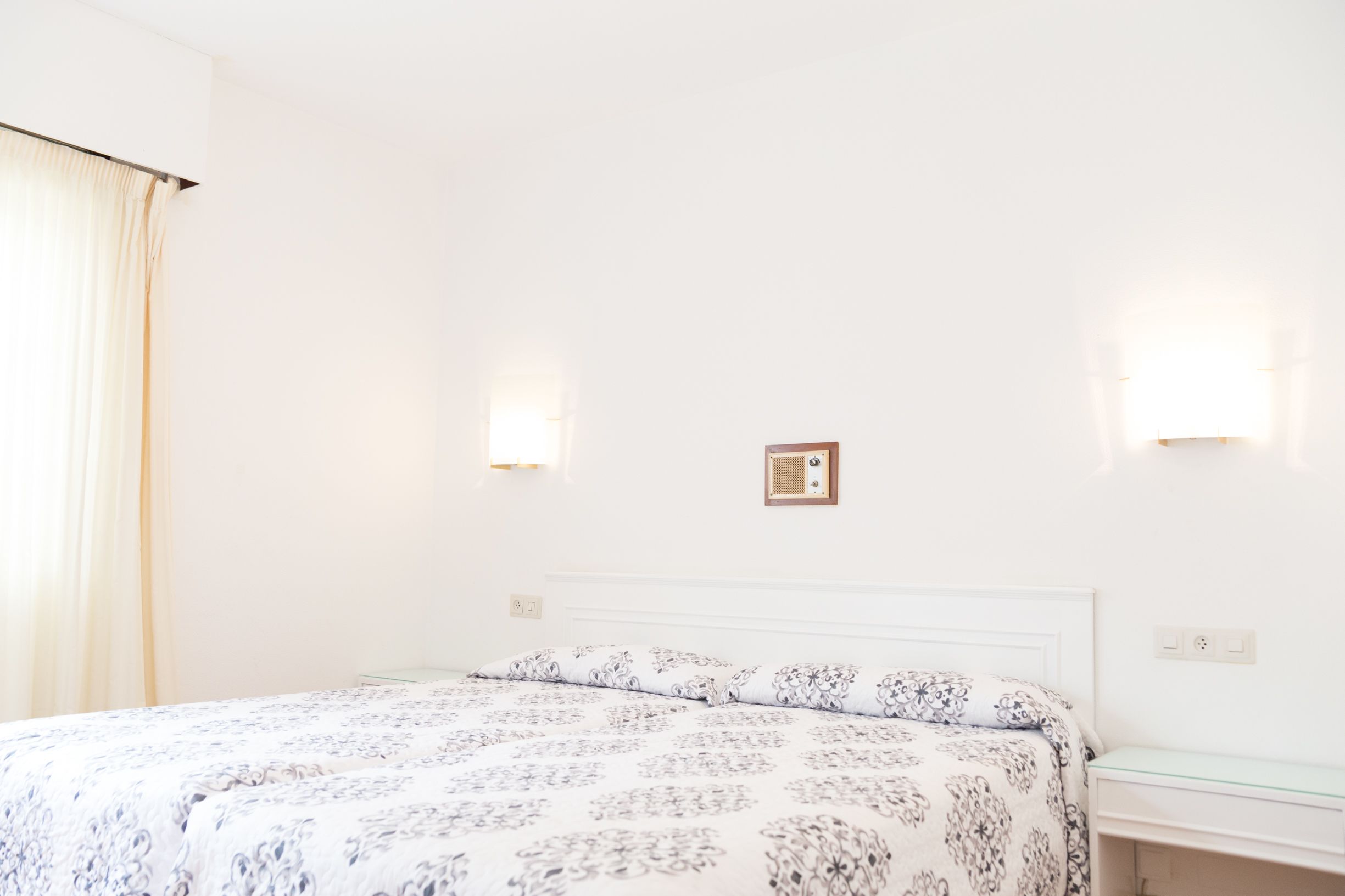 Ein Schlafzimmer mit einem Bett, einem Nachttisch und einer Wandleuchte.