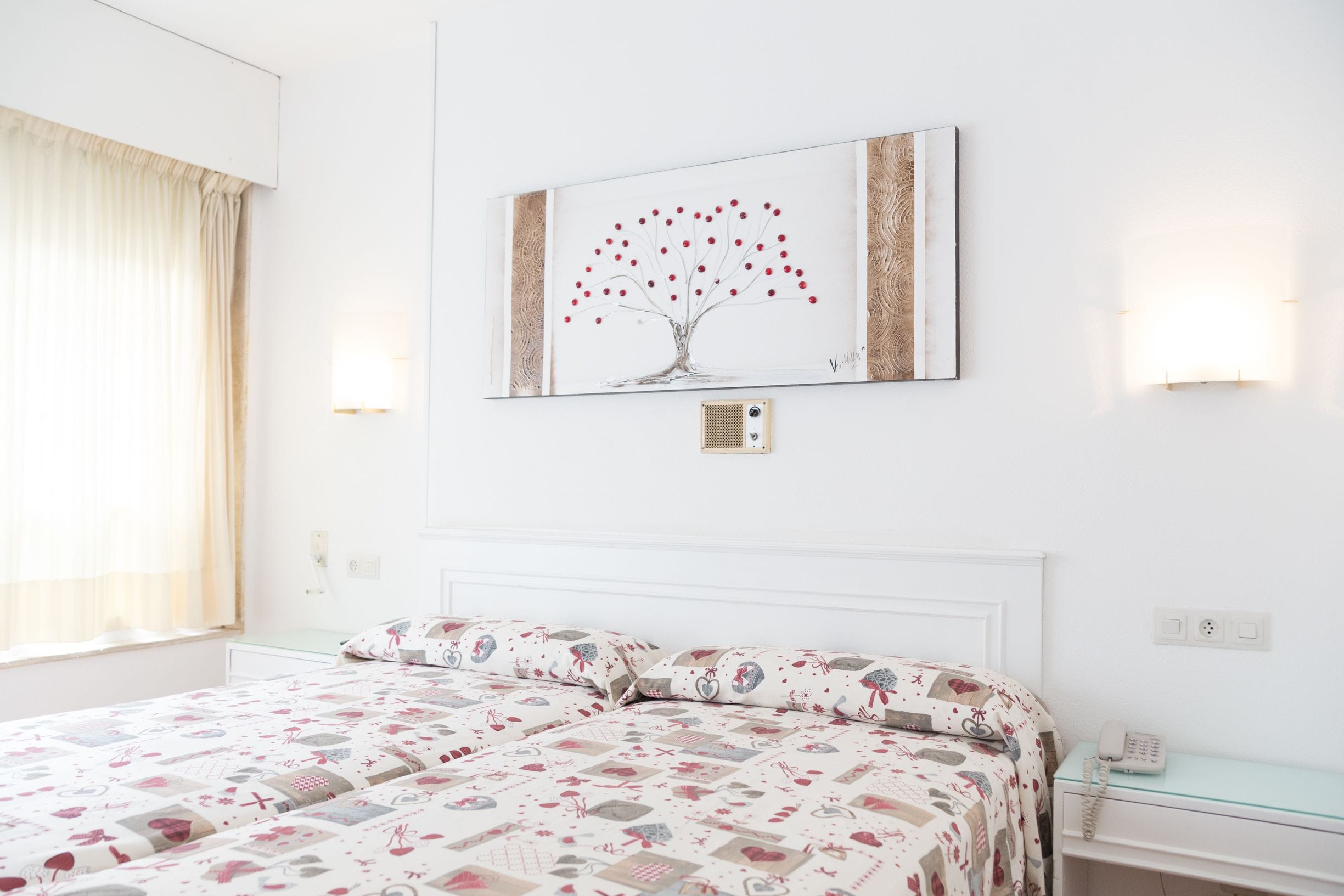 Una habitación de hotel con una cama, una mesita de noche, una lámpara y un cuadro en la pared.