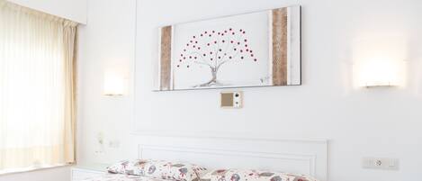 Una habitación de hotel con una cama, una mesita de noche, una lámpara y un cuadro en la pared.