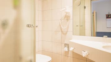 Un baño moderno con cabina de ducha de vidrio, inodoro y lavamanos con espejo.
