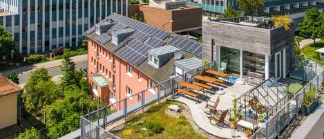 Un edificio moderno con jardín en la azotea, paneles solares y fachada de vidrio.