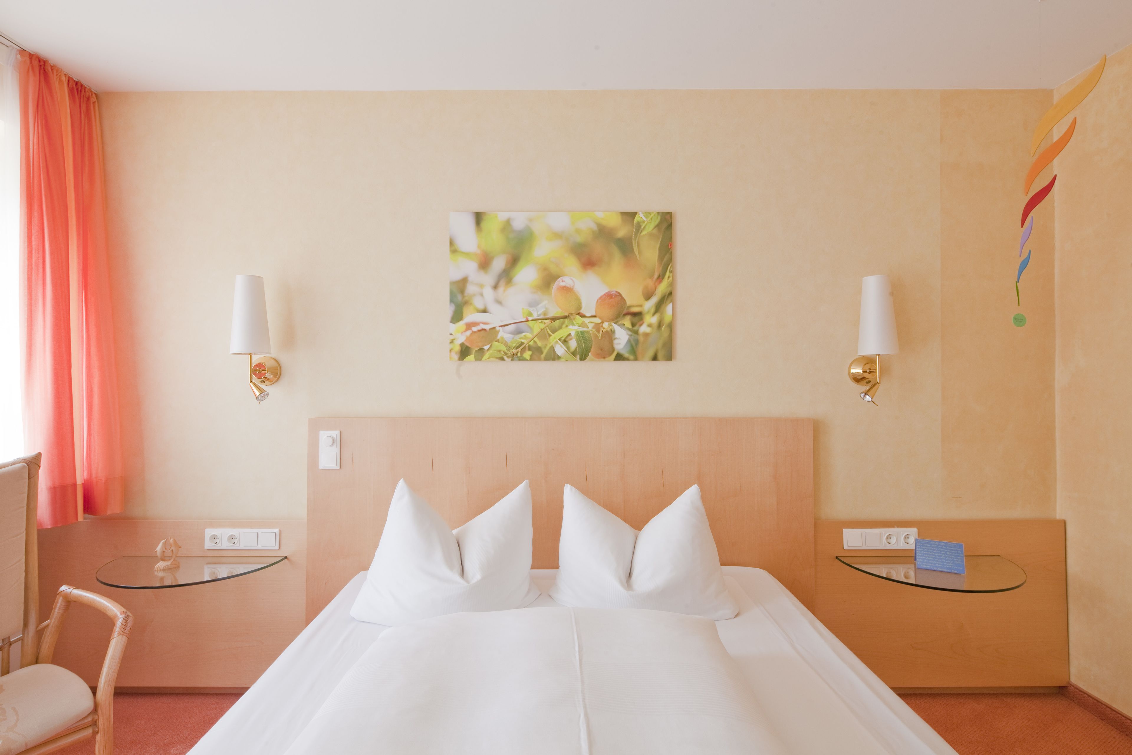 A hotel room with a bed, two bedside tables, a chair, and a wall-mounted lamp.