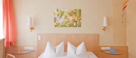 A hotel room with a bed, two bedside tables, a chair, and a wall-mounted lamp.
