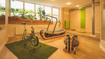 Un gimnasio moderno en casa con equipo de ejercicio, ventanas amplias y una pared de acento verde.