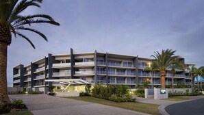 Un hôtel à plusieurs étages doté de balcons, d’une cour intérieure et de palmiers.