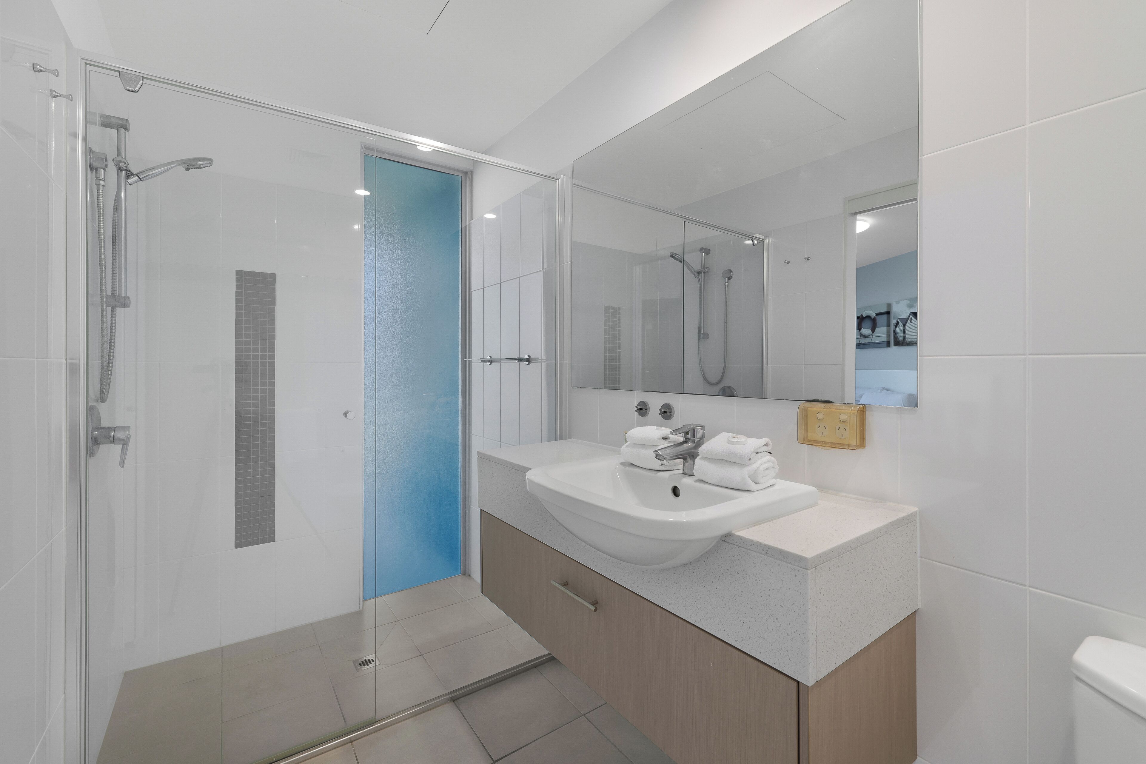 A modern bathroom with a glass-enclosed shower, a sink with a mirror, and a toilet.