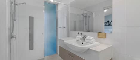 A modern bathroom with a glass-enclosed shower, a sink with a mirror, and a toilet.