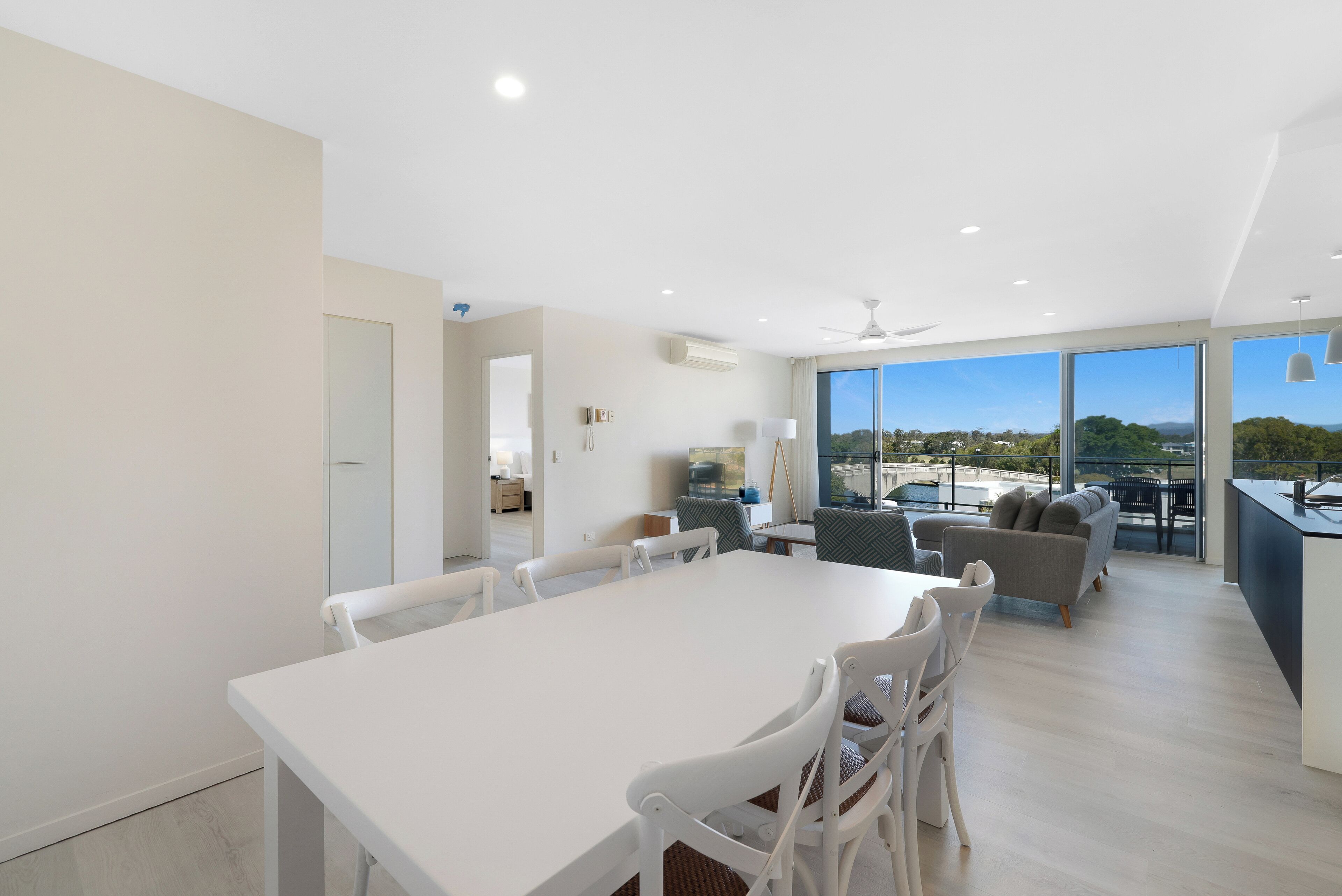 Amplia sala de estar moderna con un gran comedor, asientos cómodos y vista hacia un puerto deportivo.