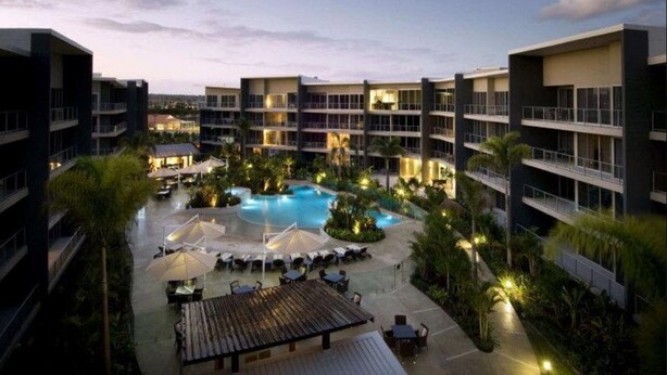 Un hôtel doté d’une piscine centrale, entourée d’espaces de détente en plein air et d’une végétation luxuriante.