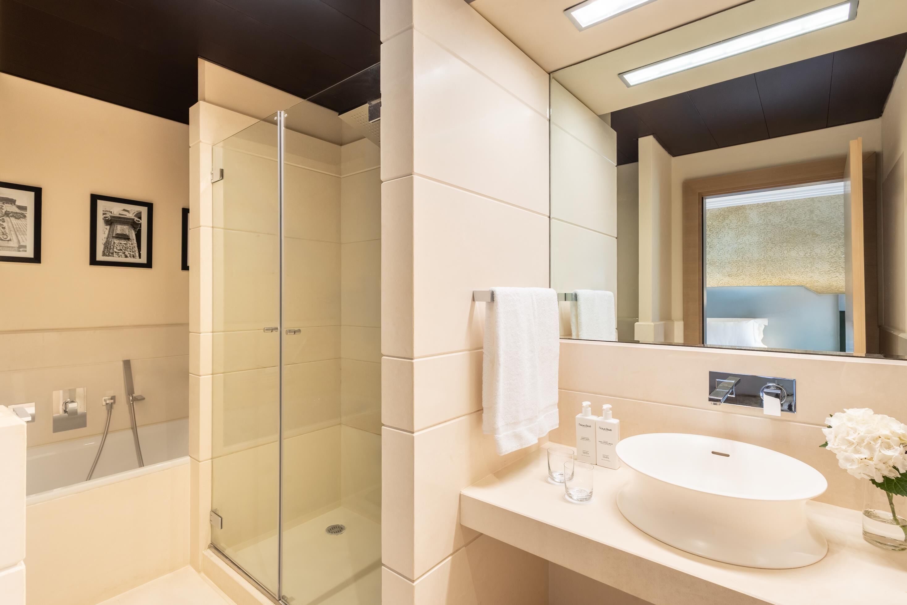 Un baño moderno con ducha envuelta en vidrio, un lavabo blanco y un espejo grande.