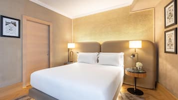 A hotel room with a large bed, two bedside tables with lamps, a door, and framed pictures on the walls.