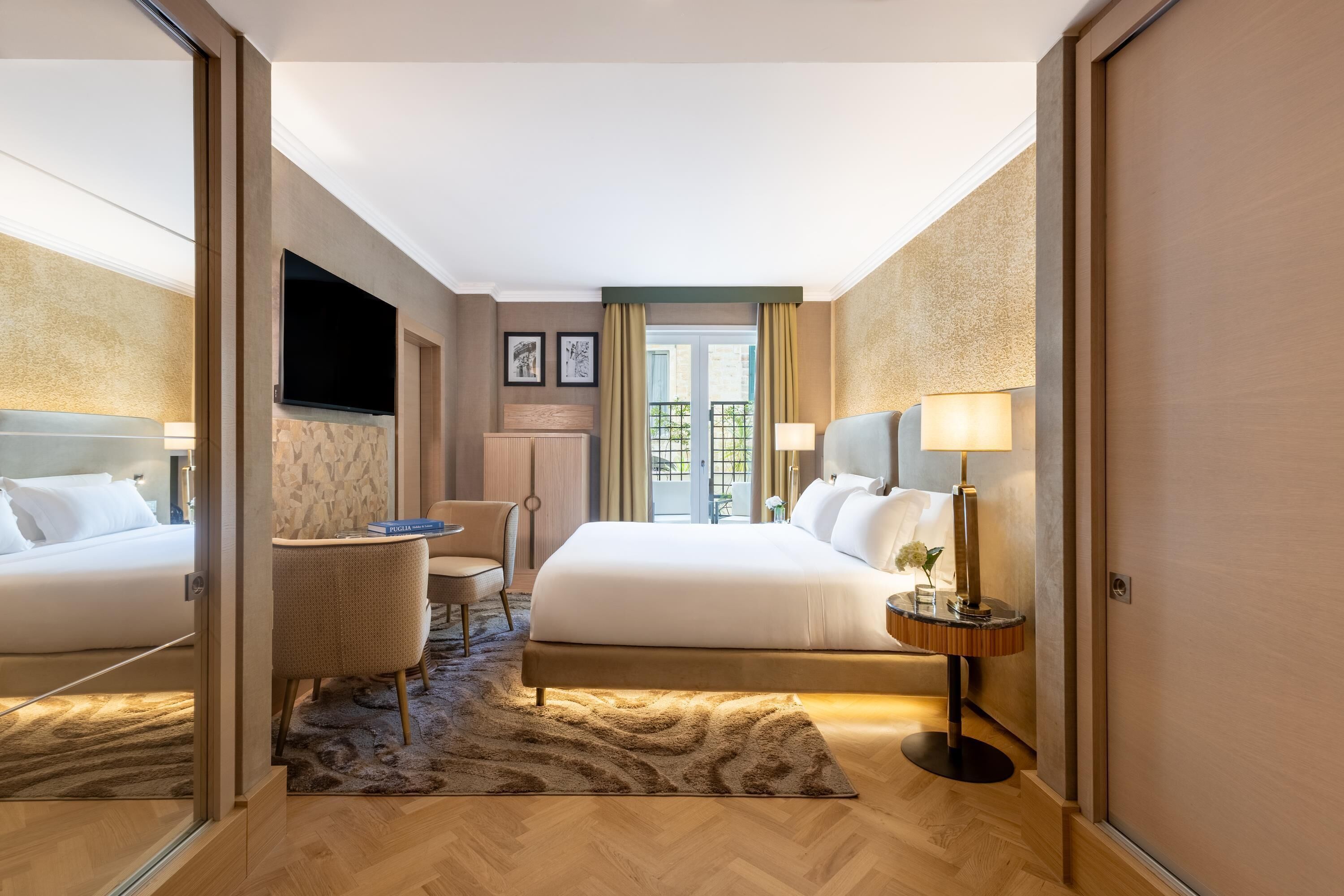 A hotel room with two beds, a TV, a desk, and a view of the outdoors.