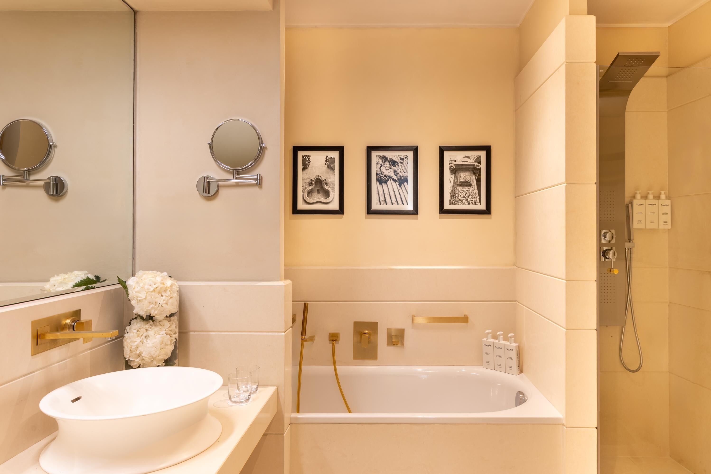 A bathroom with a white sink, a bathtub, and a shower. There are framed pictures on the wall and a mirror above the sink.