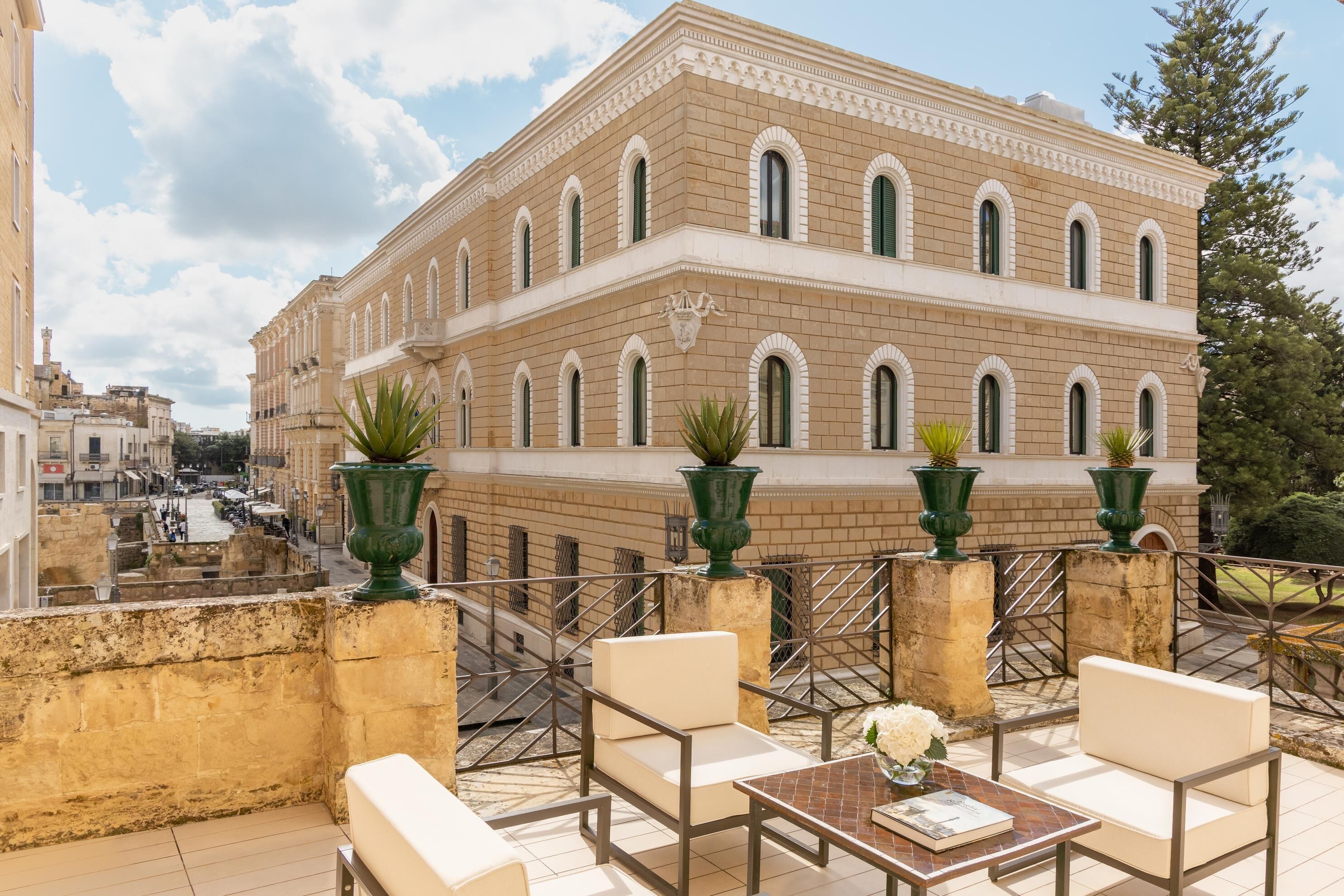 Una terraza con mobiliario exterior, vistas a un edificio histórico y un muro decorativo.