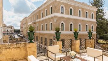 Una terraza con mobiliario exterior, vistas a un edificio histórico y un muro decorativo.