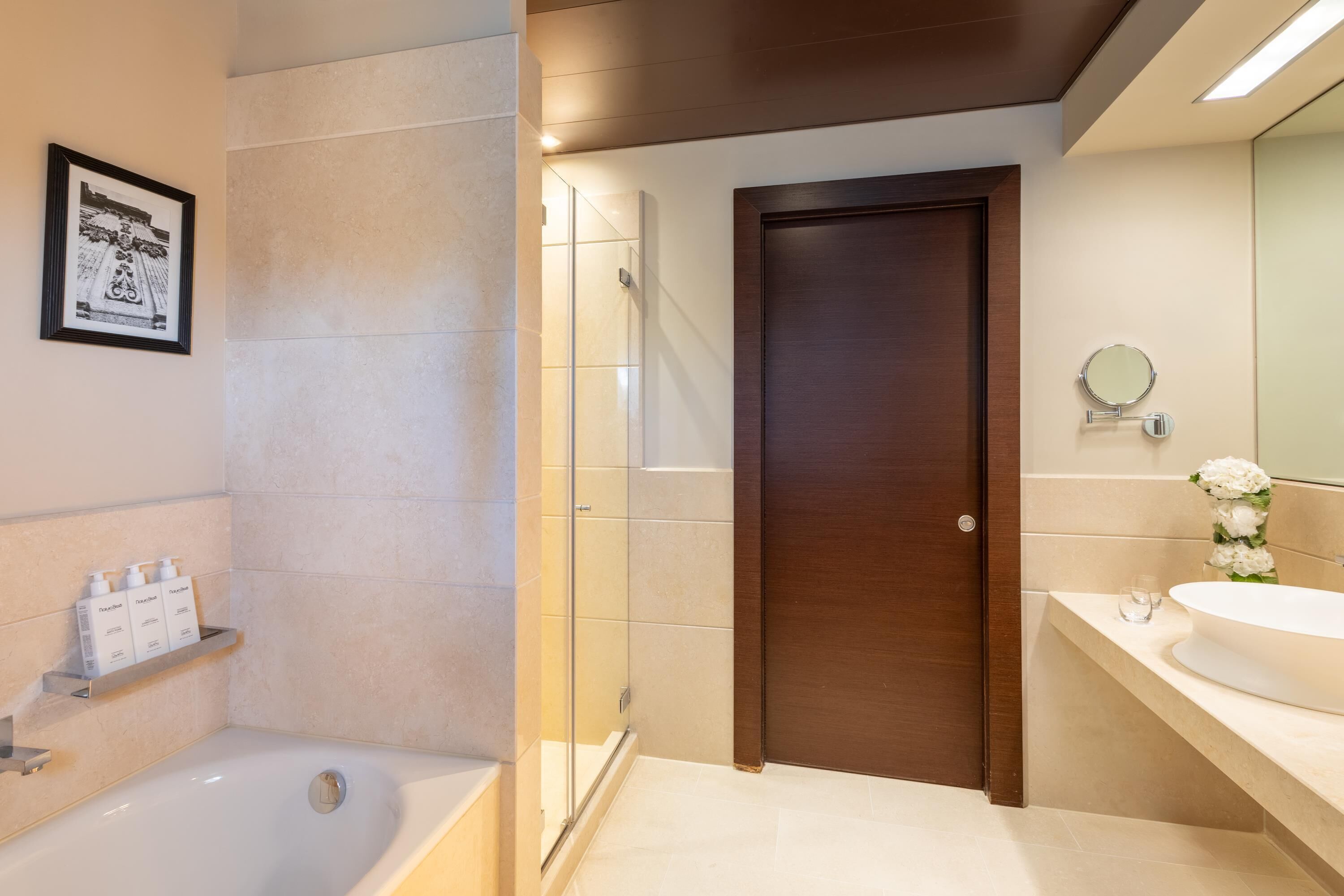 A modern bathroom with a bathtub, shower, and a large mirror.