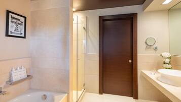 A modern bathroom with a bathtub, shower, and a large mirror.