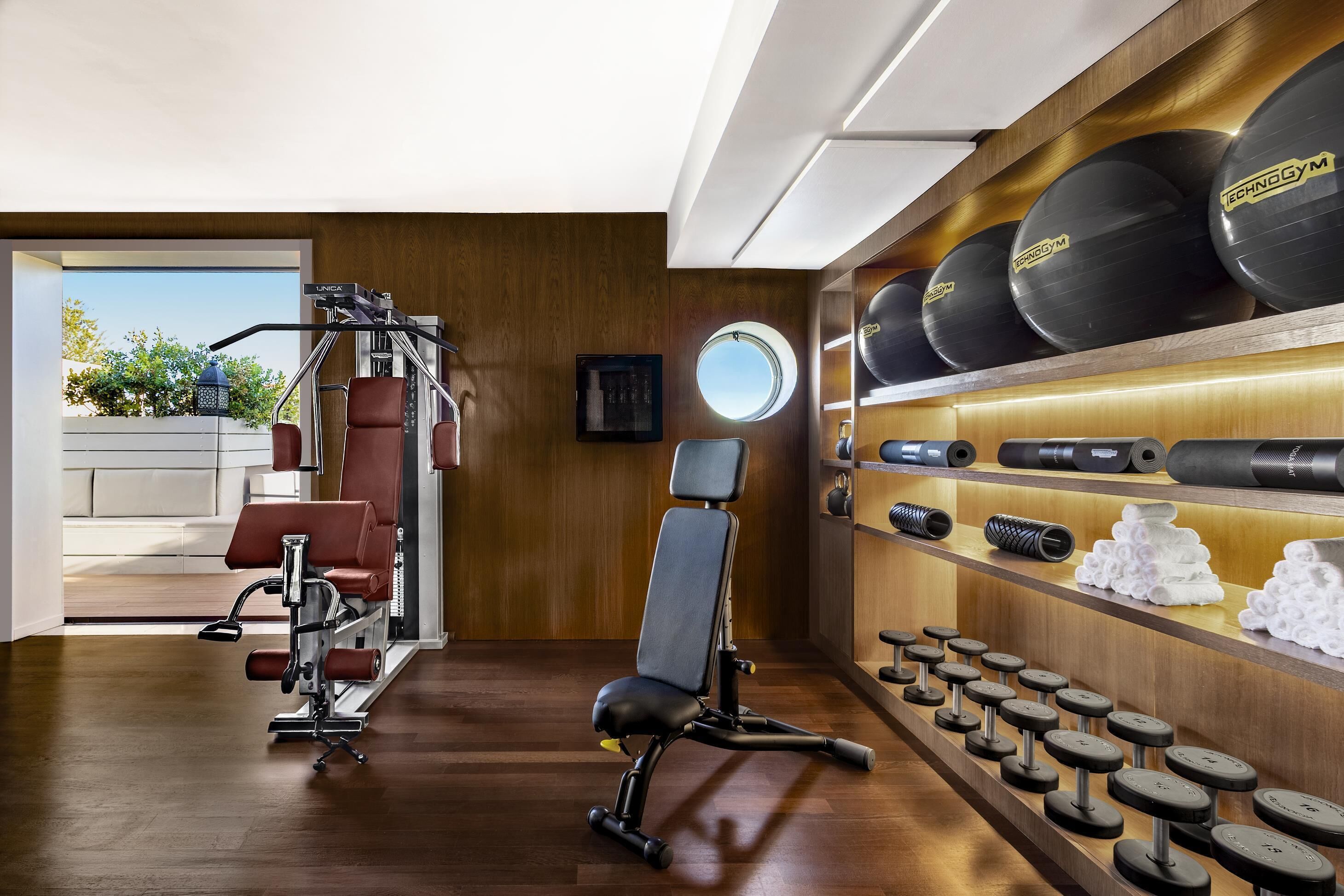 A gym with exercise equipment, dumbbells, and weight plates.