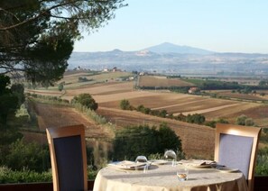 A table set for two with a view of a rural landscape, including fields and distant hills.
