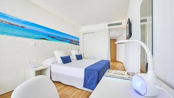 Una habitación de hotel moderna con cama, mesita de noche y escritorio con lámpara.