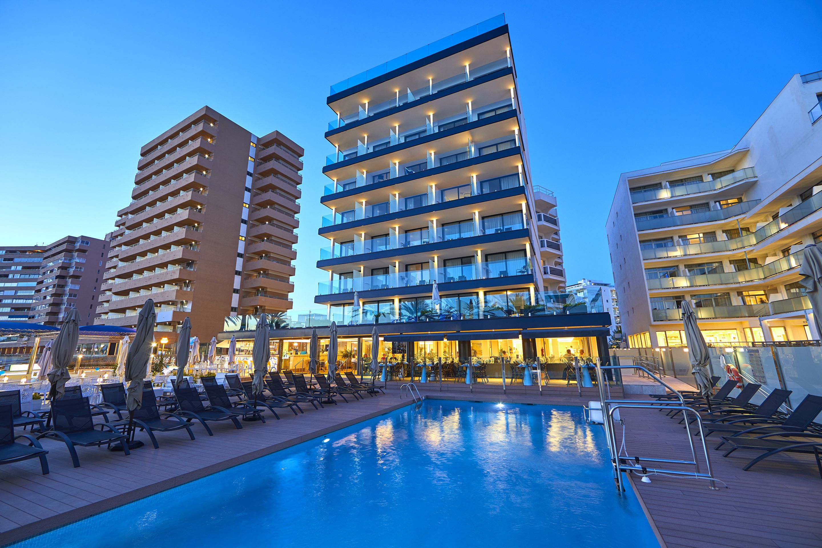 Un hotel con zona de piscina, varios balcones y un diseño arquitectónico moderno.