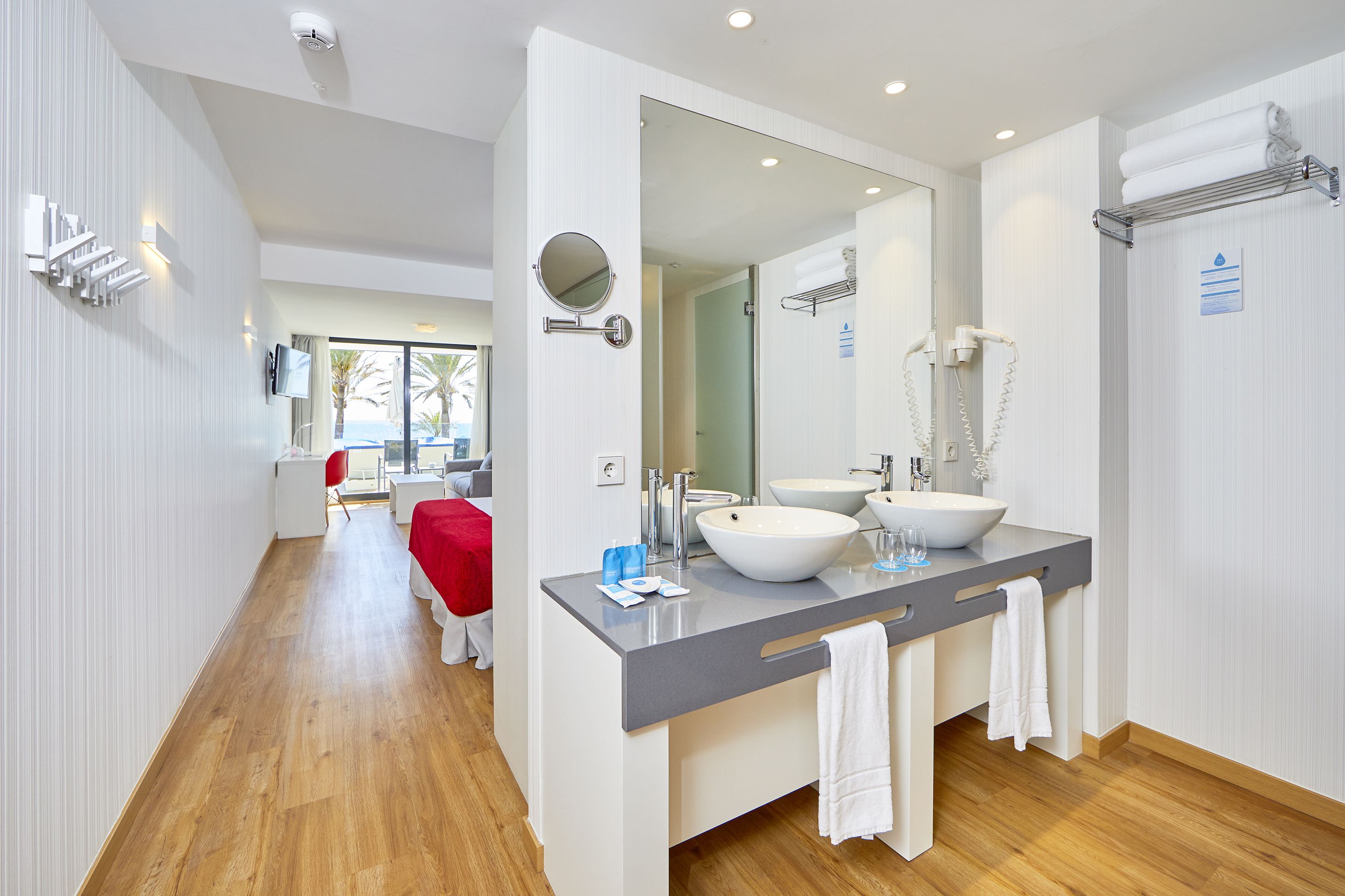 Une salle de bain moderne avec un grand miroir, deux lavabos et un espace douche.