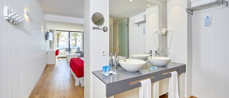 Un baño moderno con un espejo grande, dos lavamanos y una zona de ducha.
