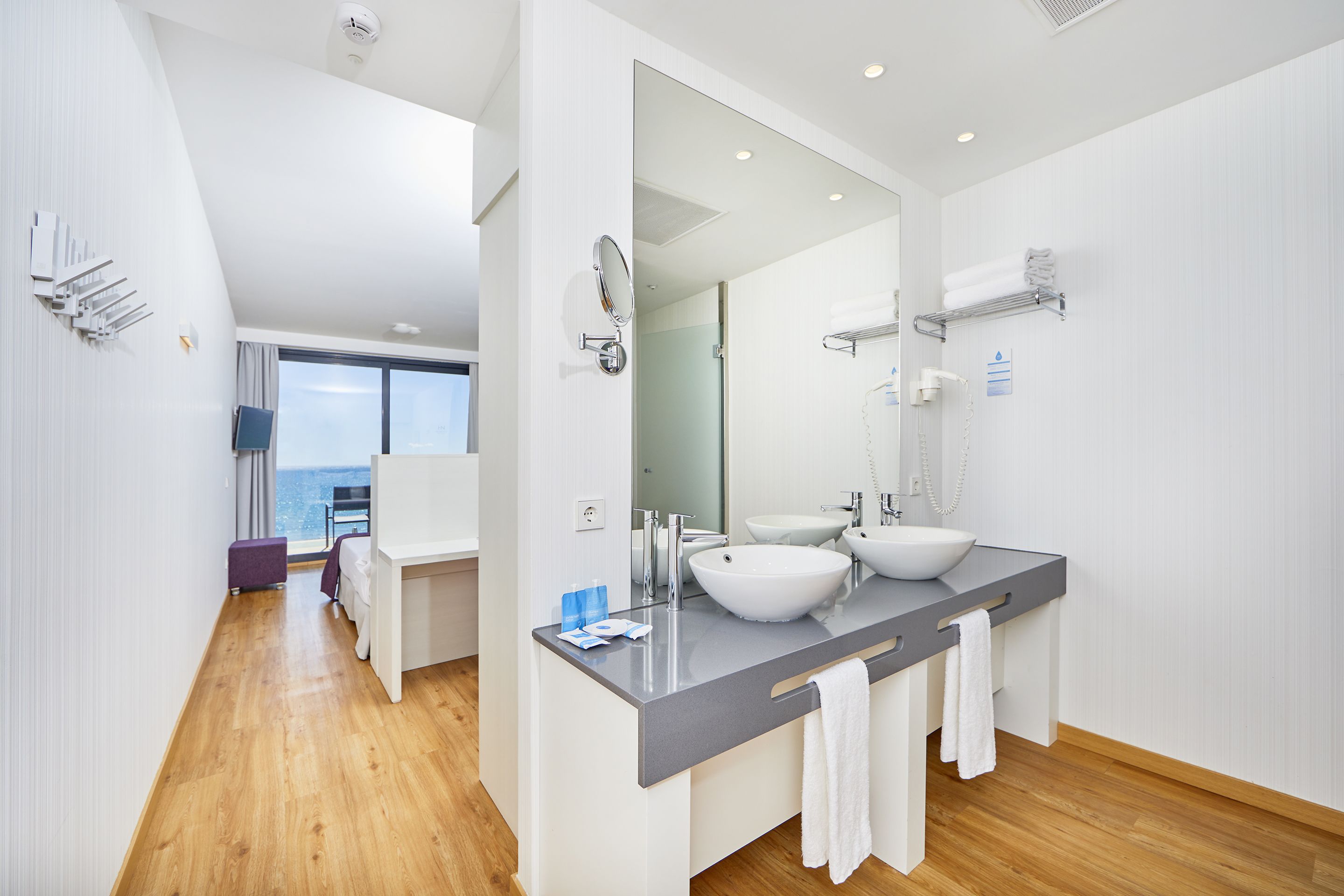 Een moderne badkamer met twee wastafels, een grote spiegel en uitzicht op de oceaan.