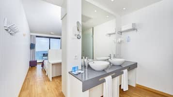 Een moderne badkamer met twee wastafels, een grote spiegel en uitzicht op de oceaan.