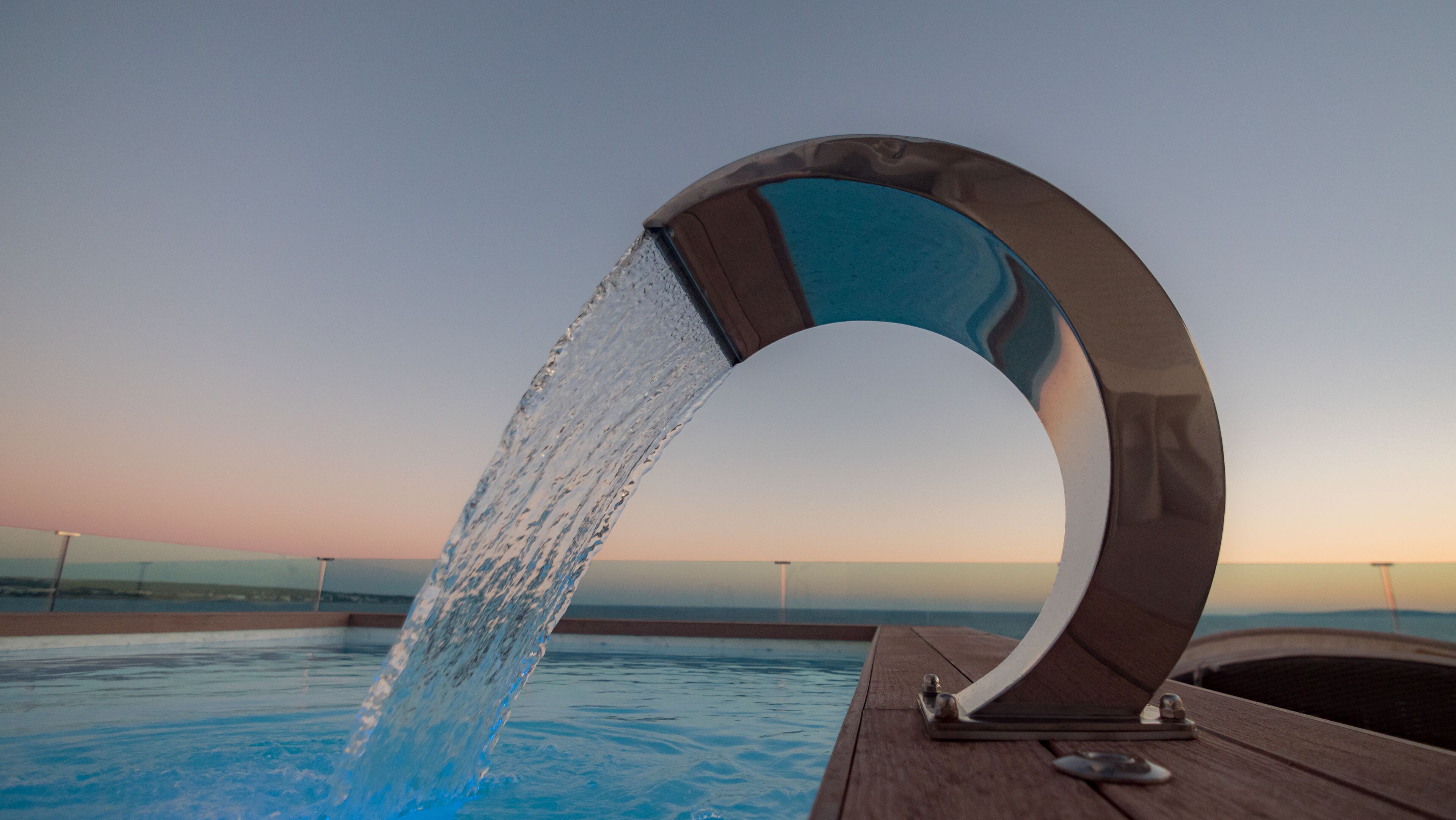 Una fuente moderna en un área de piscina con una vista despejada del horizonte.