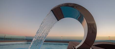 Una fuente moderna en un área de piscina con una vista despejada del horizonte.