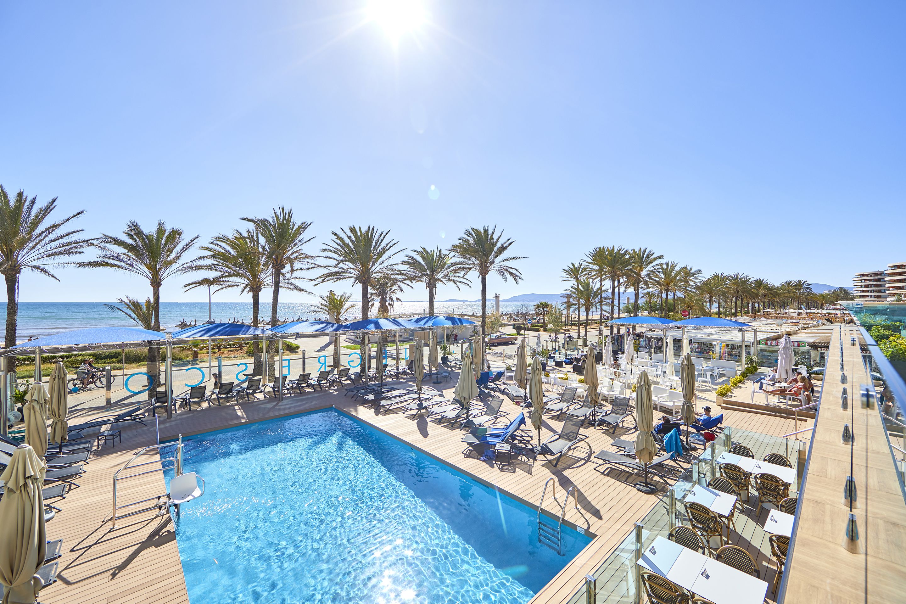 A poolside area with lounge chairs, umbrellas, and a clear view of the ocean.