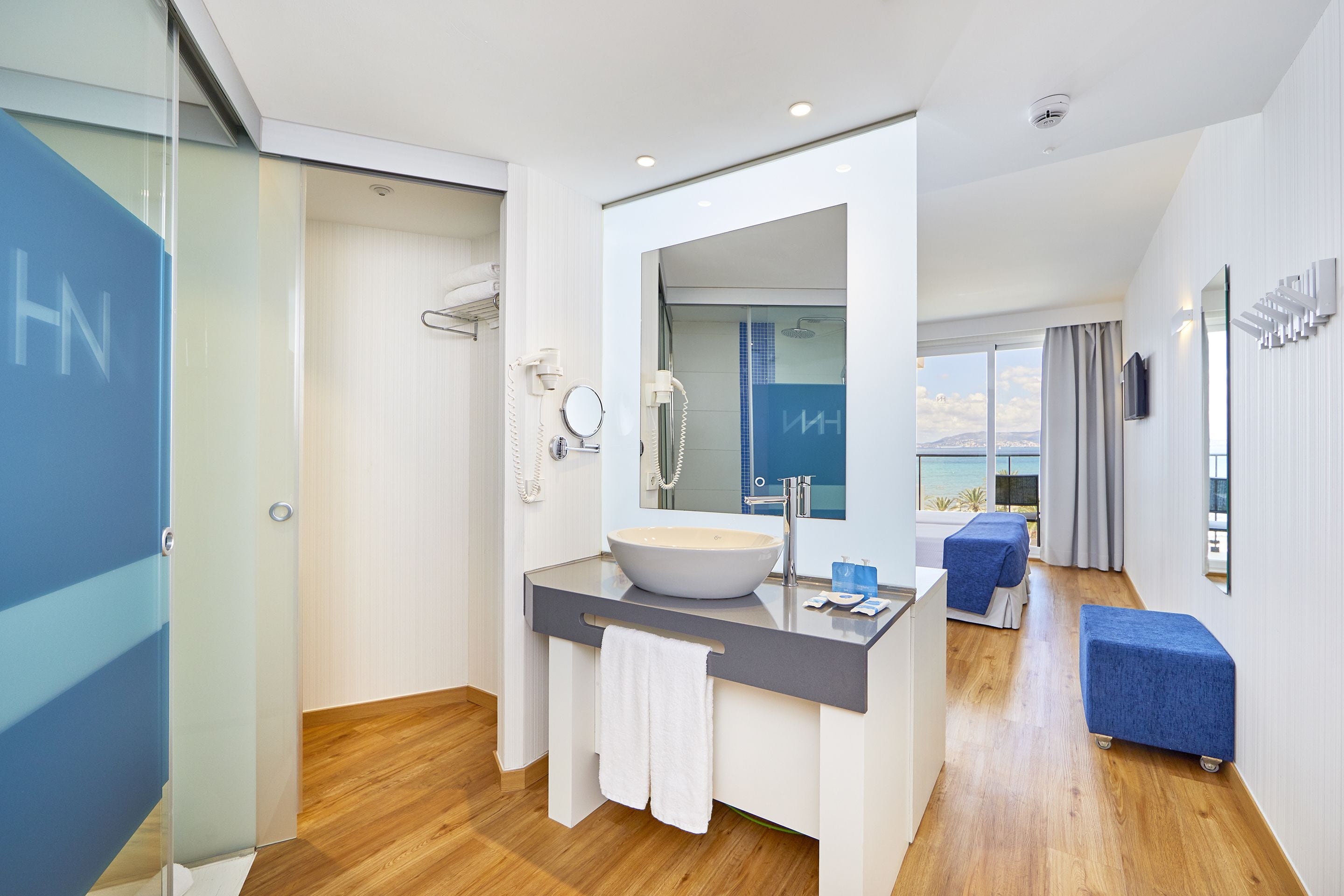 Un baño moderno con un espejo grande, un lavamanos y una ducha.