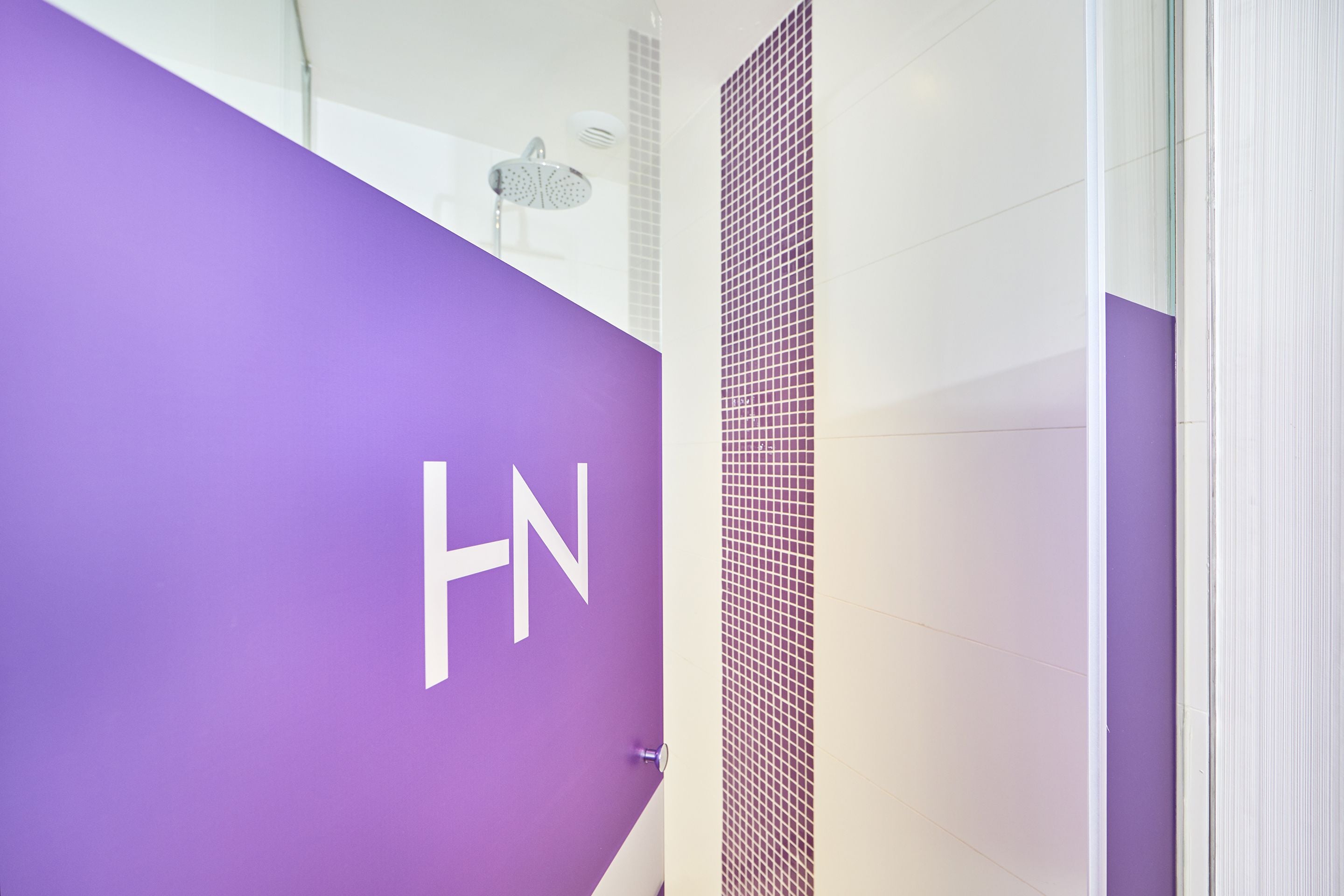 Un baño con una pared morada y una zona de ducha con azulejos.