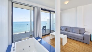 A modern hotel room with a large balcony, a bathtub, a grey sofa, and a wooden floor. - Hotel Negresco Playa de Palma - Adults Only (Palma de Mallorca)