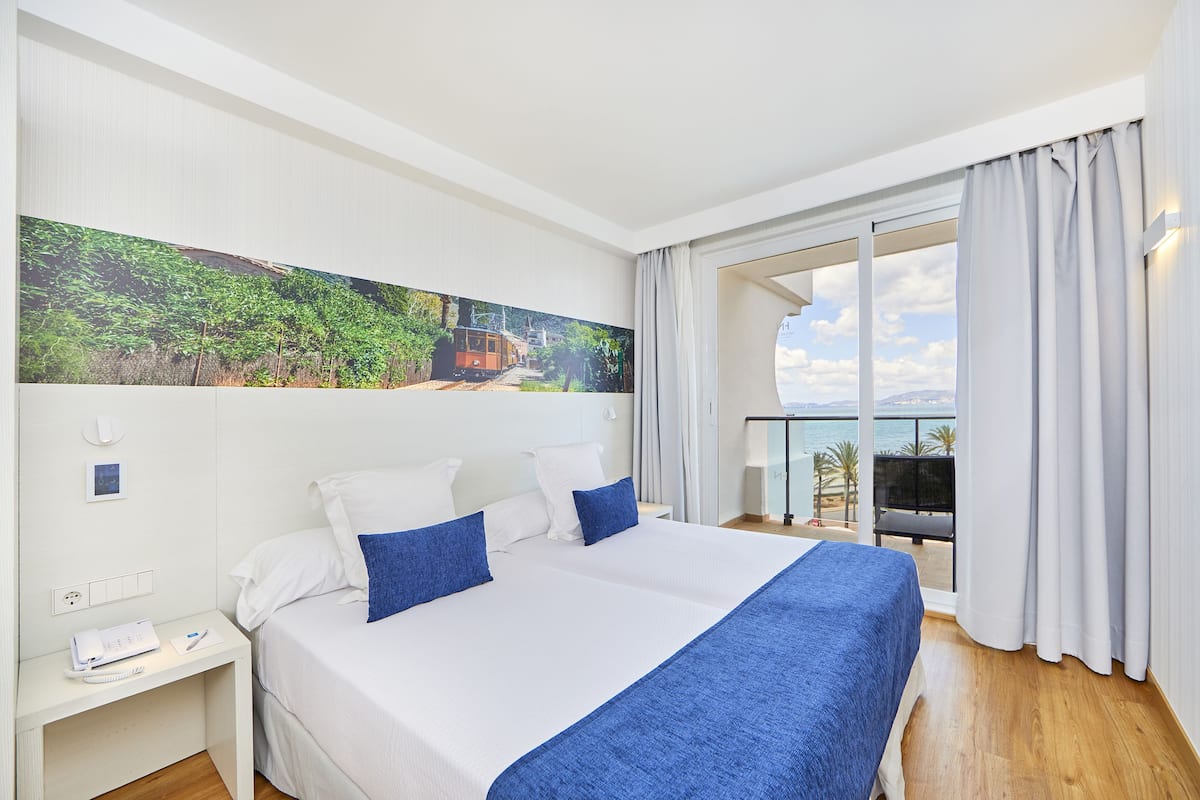 Habitación de hotel con una cama grande, vista al mar y un cuadro en la pared.