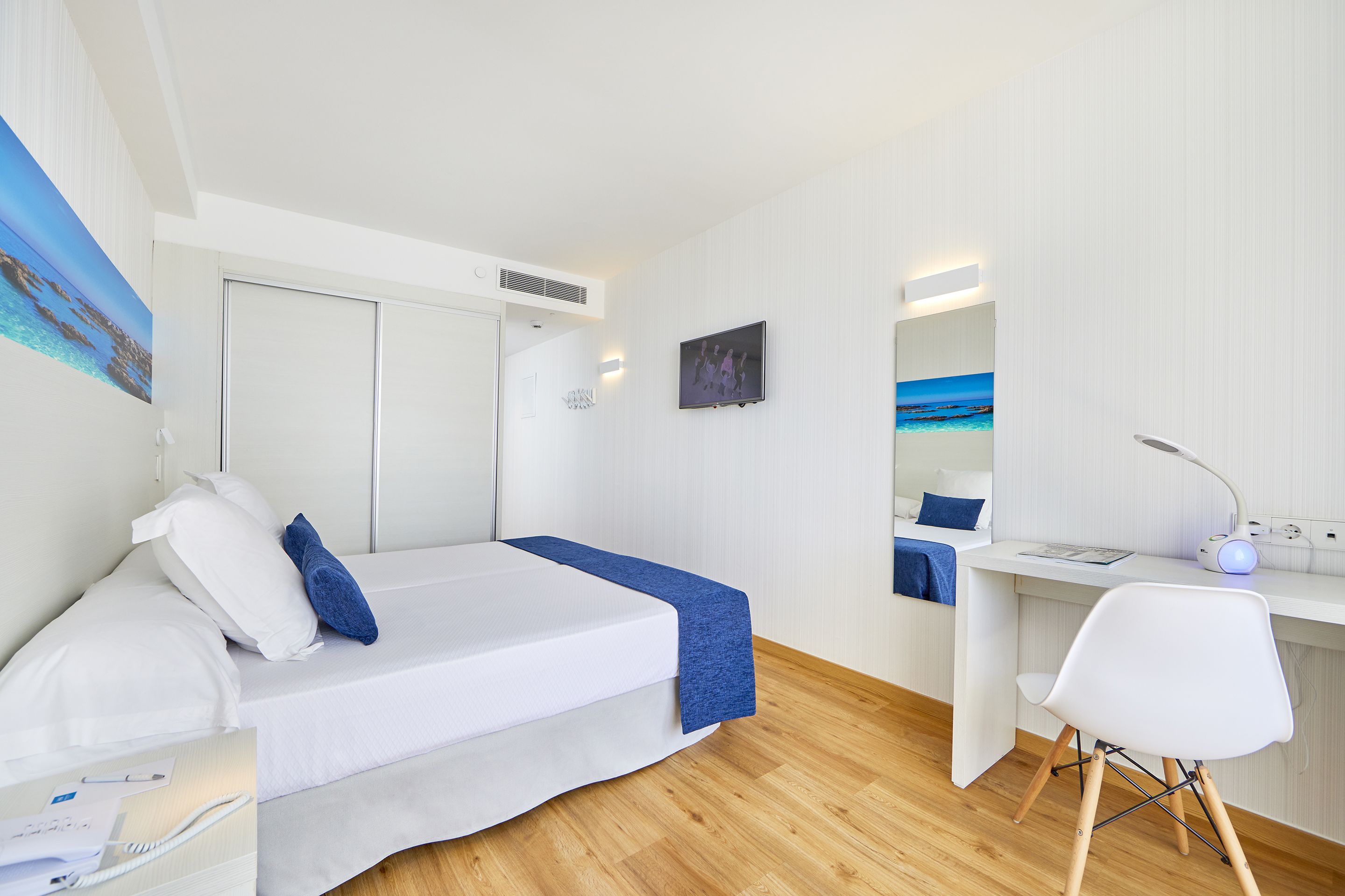 Een moderne slaapkamer met een bed, bureau en stoel.