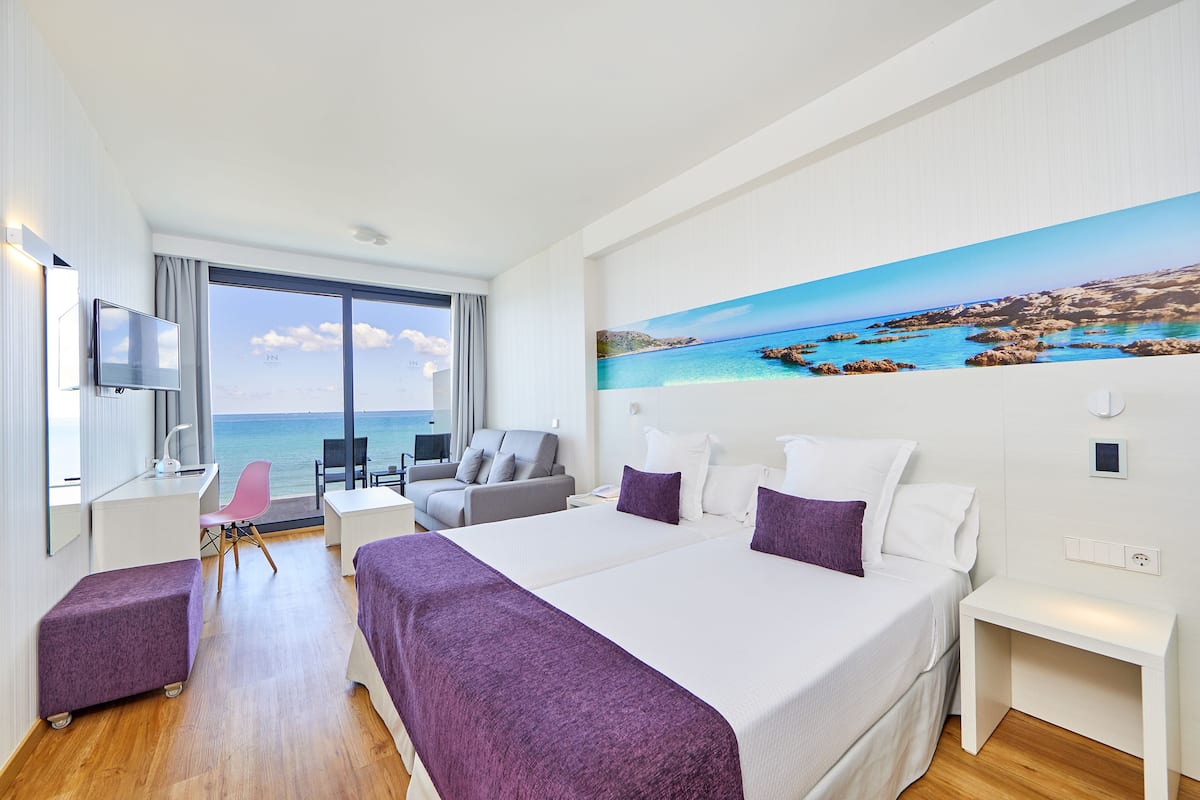 Habitación de hotel moderna con una cama grande, un escritorio, una silla y vistas al mar.