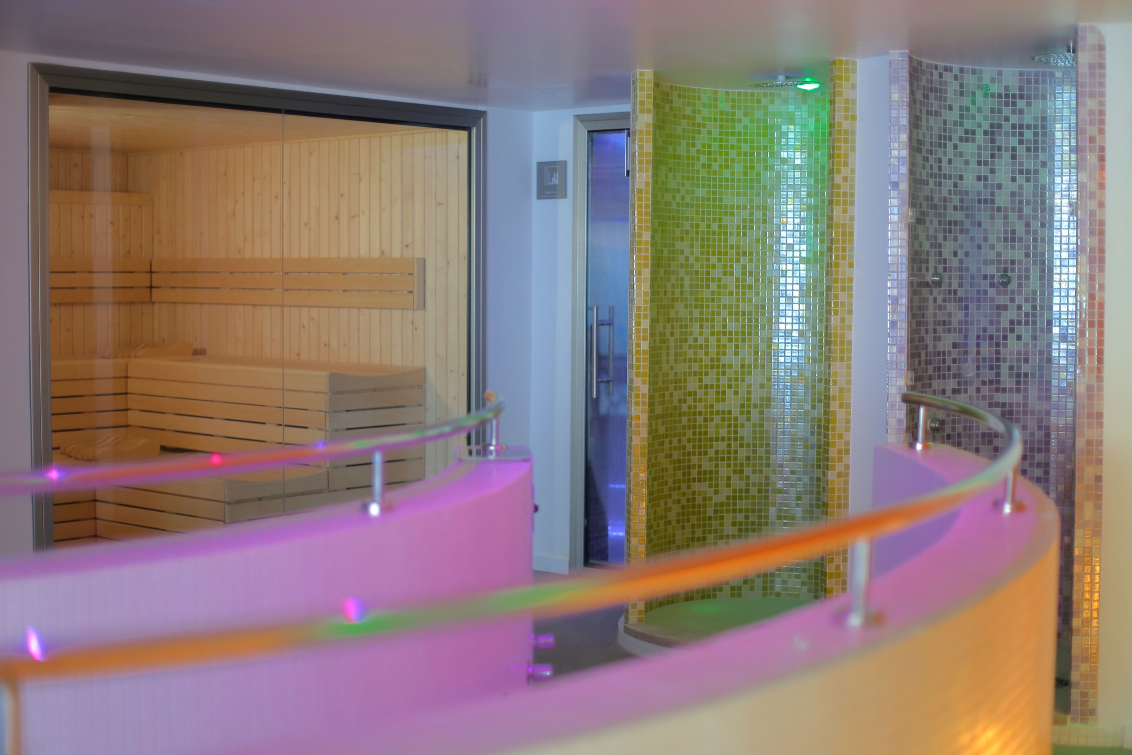 Un interior moderno con un panel de madera, una barandilla de vidrio y una pared con mosaicos.