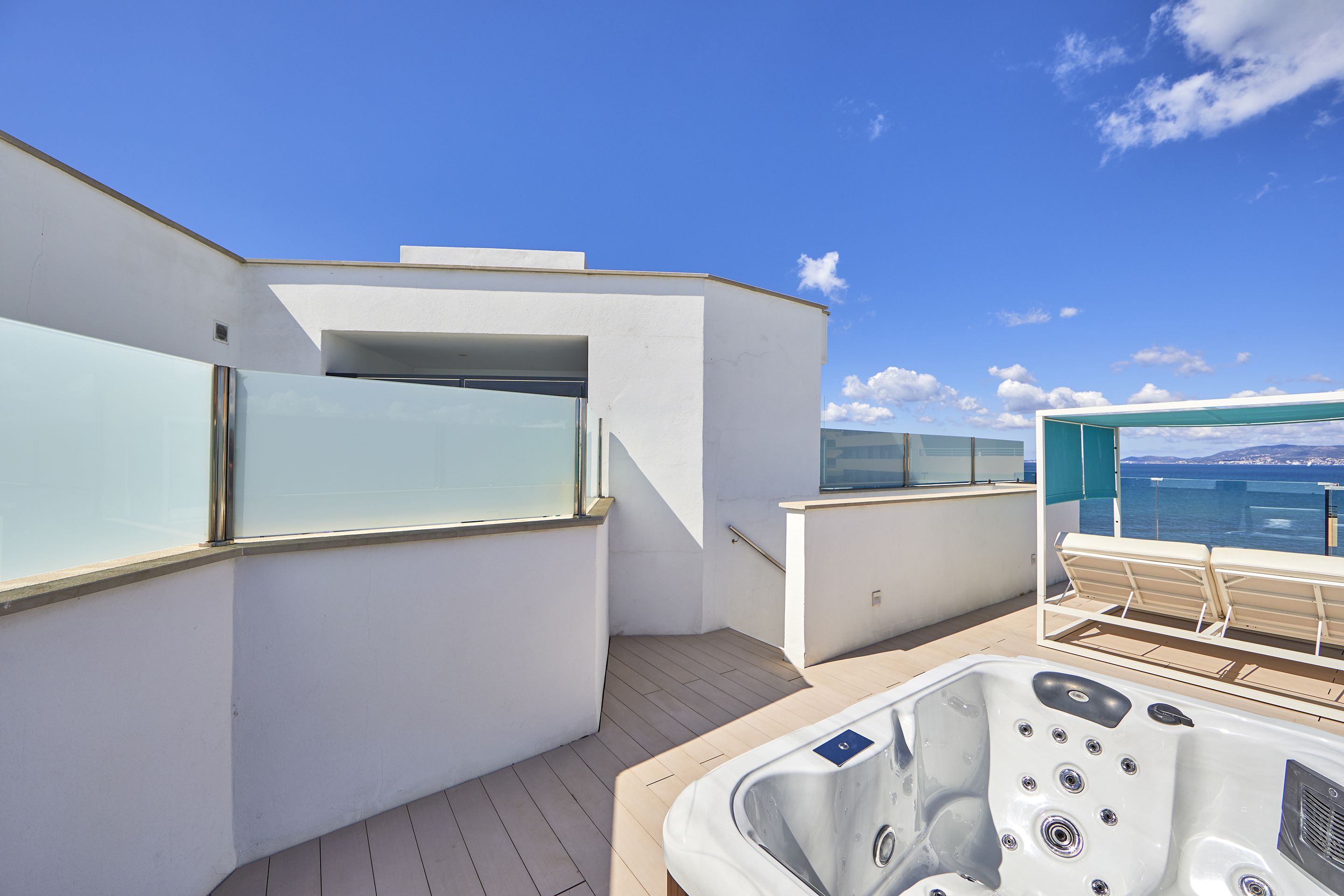 Een modern terras buiten met een jacuzzi, een zithoek en uitzicht op zee.