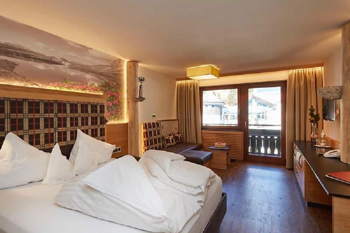 Une chambre d’hôtel avec un lit, un bureau, un banc et une vue sur l’extérieur.