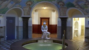 A hallway with a central pool, a statue, and arched doorways. - Alpenrose - Wellnessresort (Elbigenalp)