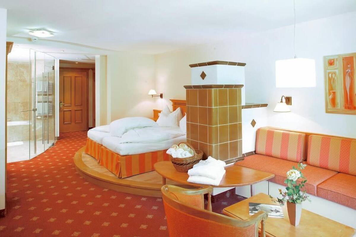 A hotel room with a bed, a sofa, a small table, a lamp, and a decorative wall piece.